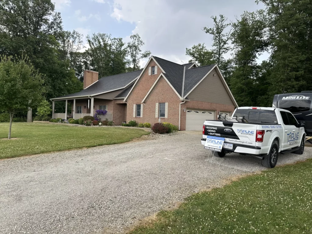 brick house with shingle roof. White Topline Roofing truck parked in driveway Tiffin, Ohio